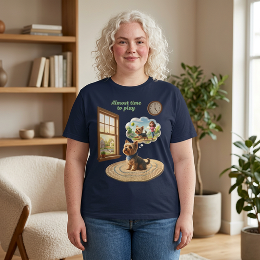 Person wearing a navy blue t-shirt with a dog and window design, standing in a room with a bookshelf and plants.